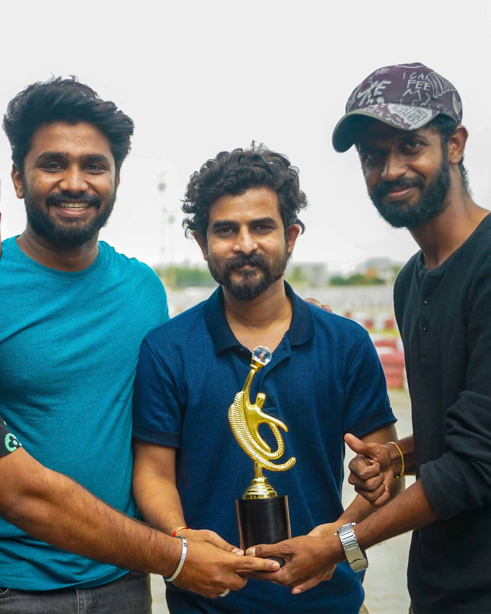 Three individuals standing together, holding a trophy after a race.
